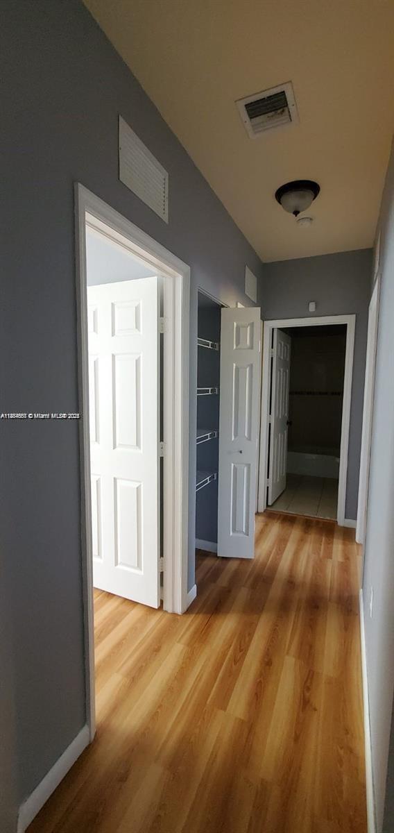 A hallway with wood-look flooring leads to two open doorways and a closet — 60 SE 6th Rd, Homestead FL 33030, HOMESTEAD, FL
