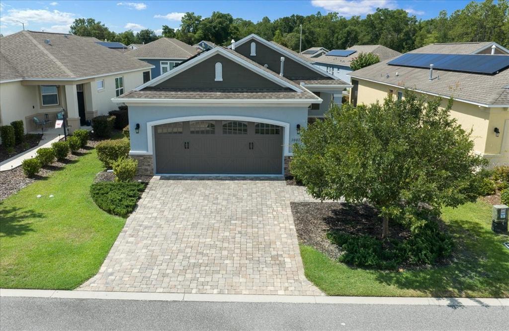 A light blue house with a stone-accented garage and a paved driveway — 10018 SW 98TH LANE, OCALA, FL