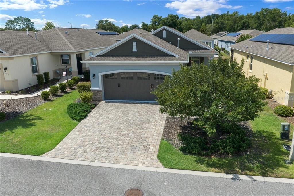 An aerial view of a suburban house with a paved driveway and a large tree — 10018 SW 98TH LANE, OCALA, FL
