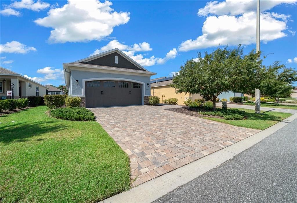 A single-story house with a paved driveway and a two-car garage under a blue sky — 10018 SW 98TH LANE, OCALA, FL