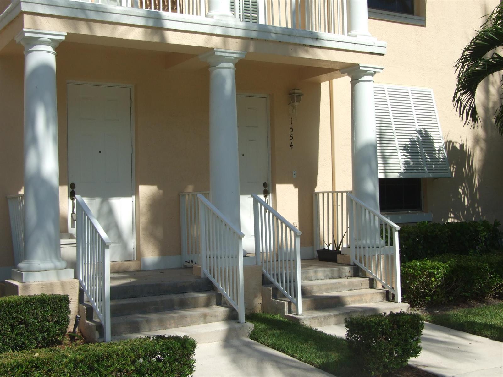 The exterior of a building features two white doors, concrete steps, and white columns — 1554 Limetree Bay Avenue, Jupiter FL 33458, JUPITER, FL