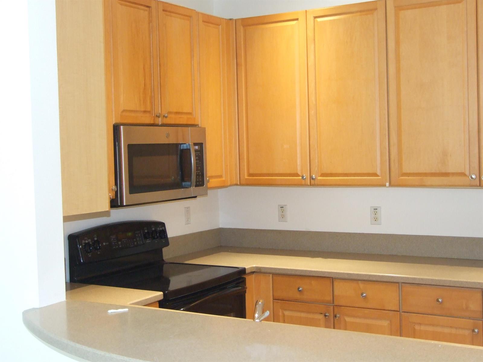 A kitchen features light wood cabinets, stainless steel appliances, and tan countertops — 1554 Limetree Bay Avenue, Jupiter FL 33458, JUPITER, FL