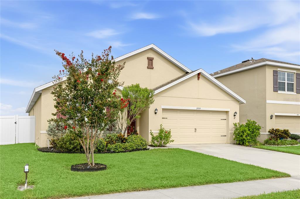 A single-story suburban house with a beige stucco exterior, a two-car garage, and front landscaping — 3909 PARK WILLOW AVENUE, PALMETTO, FL