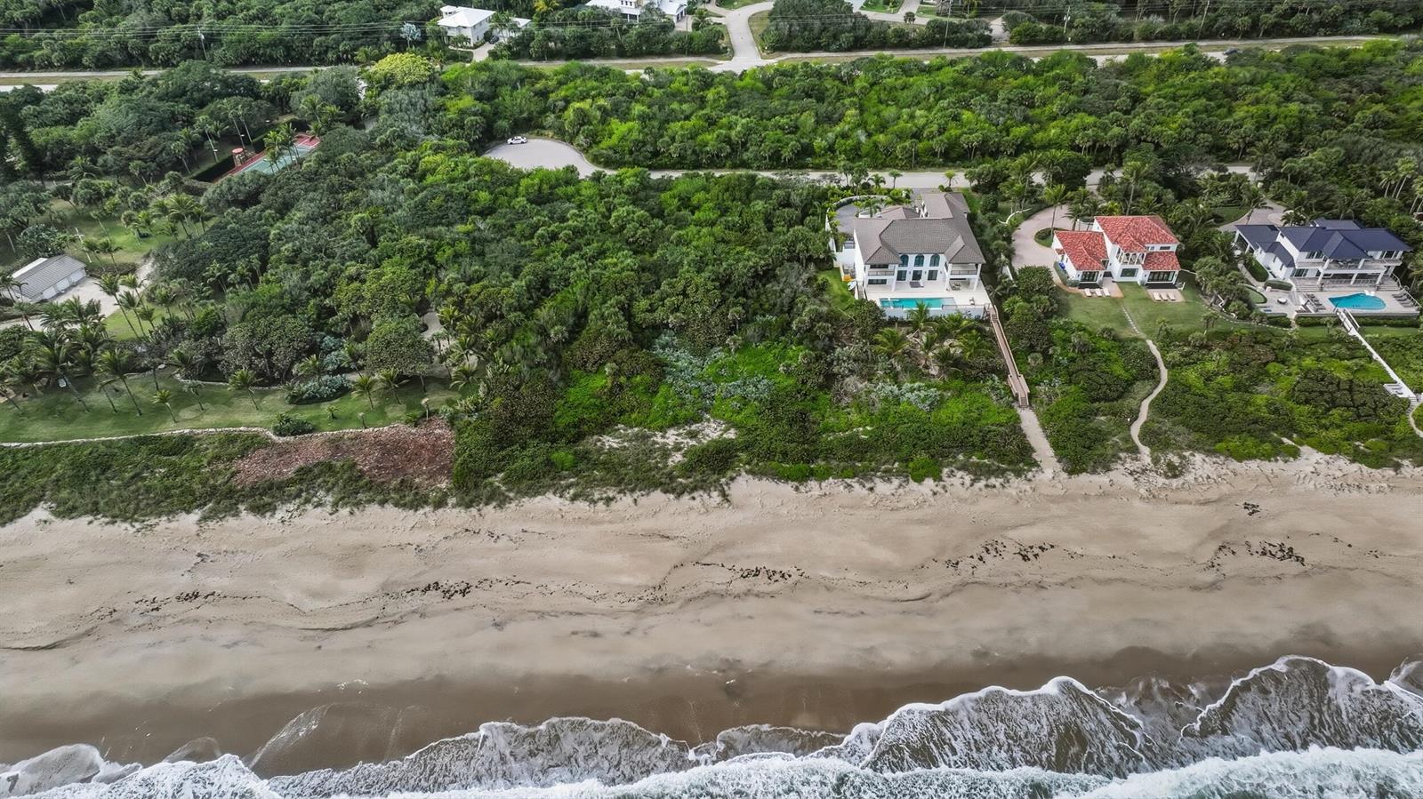 An aerial view shows three beachfront houses surrounded by dense vegetation along the coastline — 11740 Seaview Drive, Vero Beach FL 32963, VERO BEACH, FL