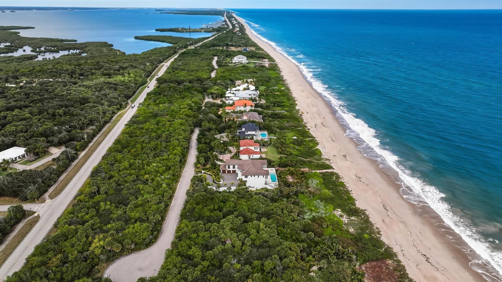 An aerial view shows a coastal road, dense vegetation, and beachfront houses along the ocean — 11740 Seaview Drive, Vero Beach FL 32963, VERO BEACH, FL