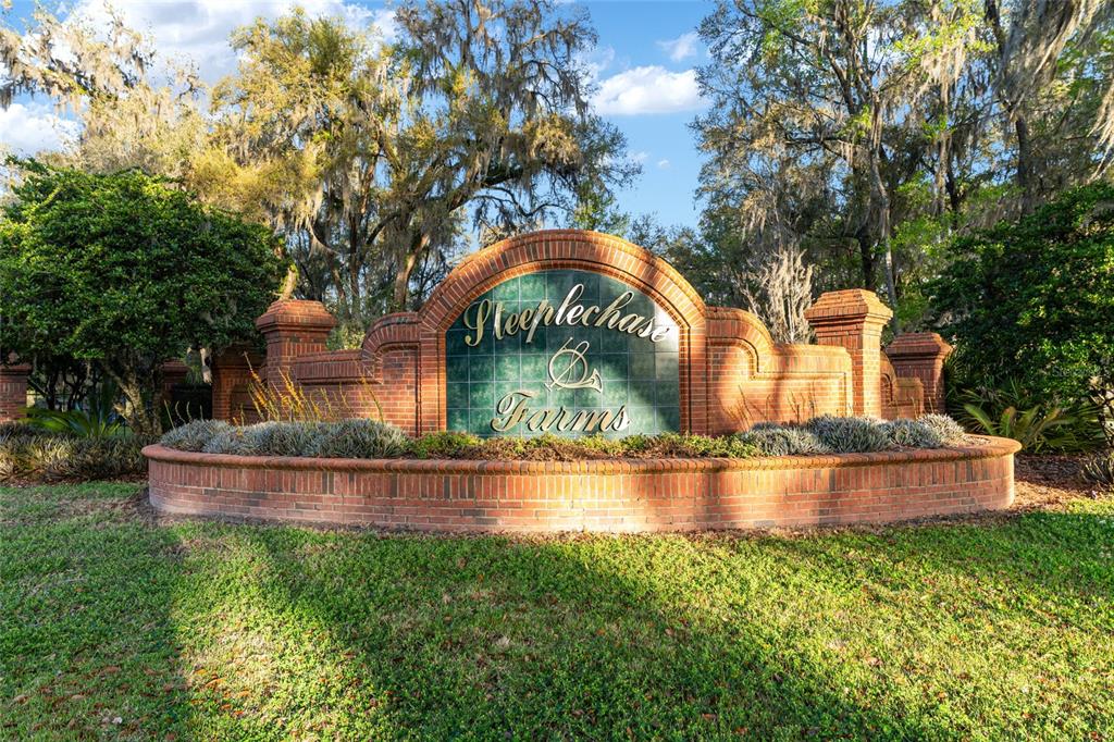 A brick entrance sign for Steeplechase Farms sits in a grassy area with mature trees — 14312 NW 41ST AVENUE, NEWBERRY, FL