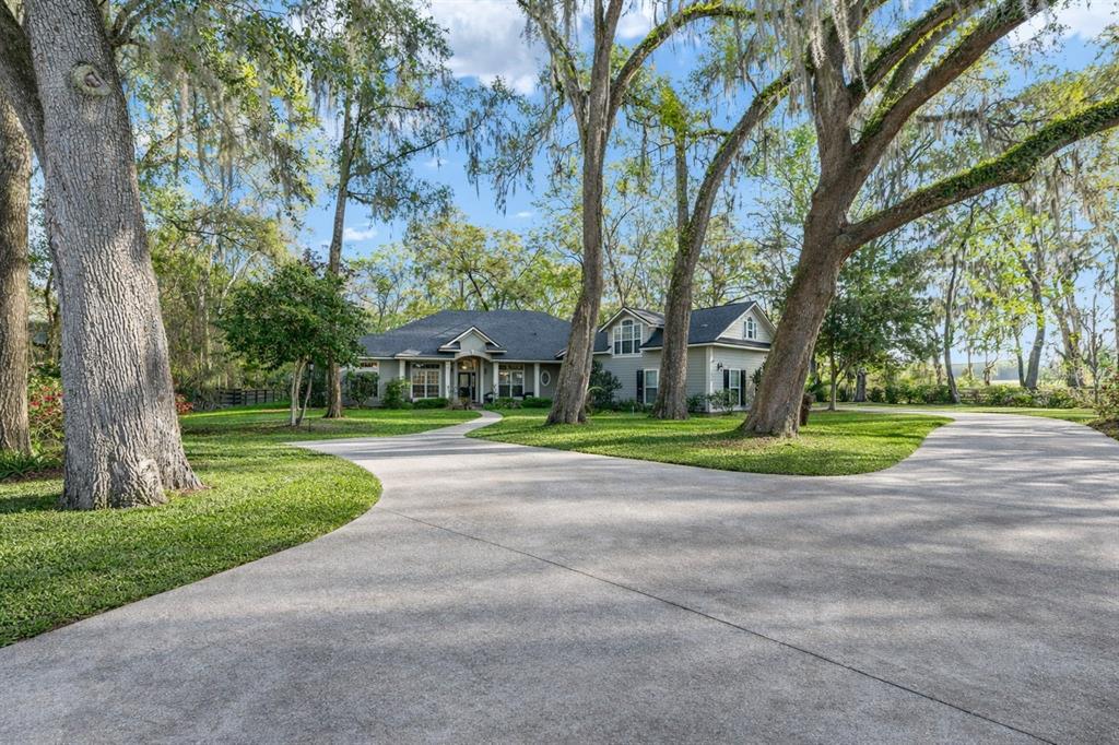 A house with a concrete driveway and large trees with Spanish moss in the yard — 14312 NW 41ST AVENUE, NEWBERRY, FL