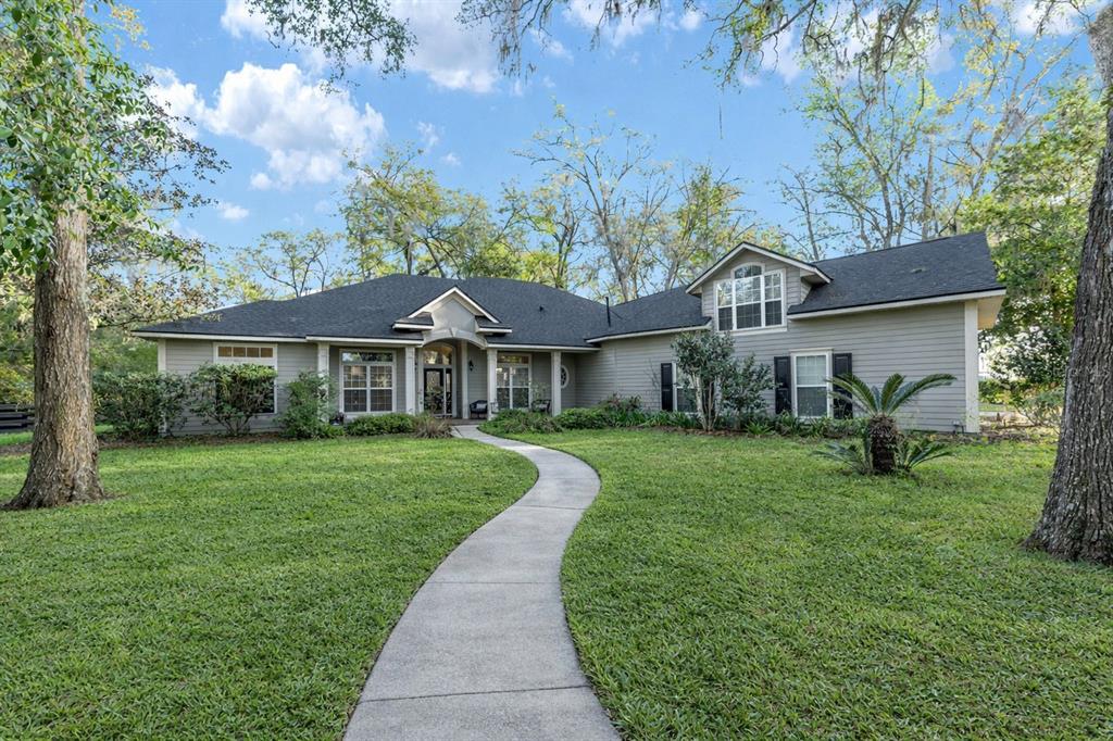A single-story house with gray siding, a dark shingled roof, and a curved concrete walkway — 14312 NW 41ST AVENUE, NEWBERRY, FL