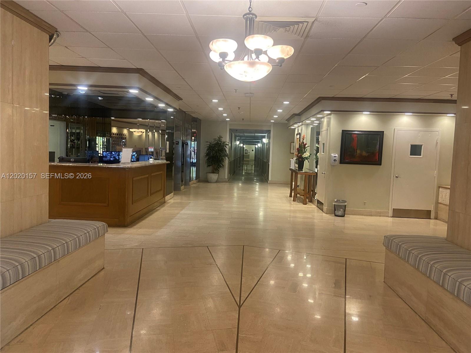 The lobby features a reception desk, a central chandelier, and seating areas on both sides — LAUDERDALE BY THE SEA, FL