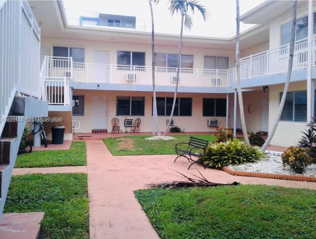 An exterior view of a two-story apartment complex with a central courtyard and walkway — 350 75th St # 109, Miami Beach FL 33141, MIAMI BEACH, FL