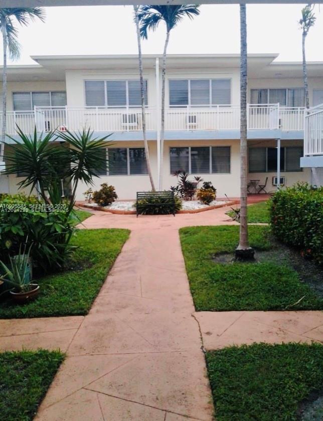 A two-story apartment building exterior features a central walkway, landscaping, and a small bench — 350 75th St # 109, Miami Beach FL 33141, MIAMI BEACH, FL
