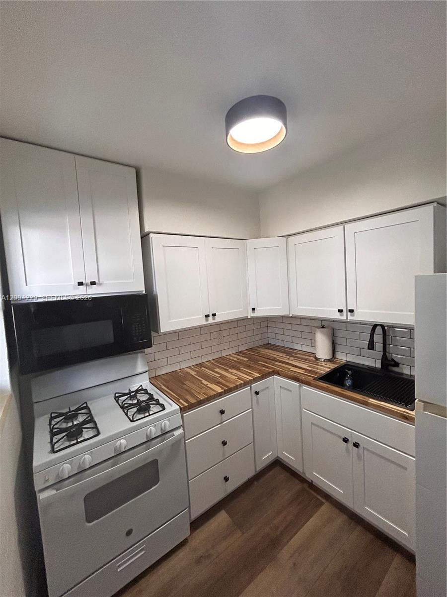 A kitchen features white cabinets, a wood countertop, a black sink, and a gas stove — 350 75th St # 109, Miami Beach FL 33141, MIAMI BEACH, FL