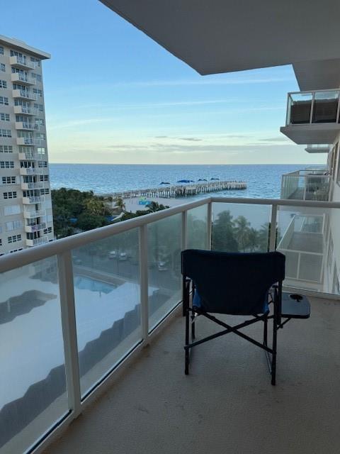 A balcony with a folding chair overlooks a beach, a pier, and the ocean — 111 N Pompano Beach Boulevard # 1005, Pompano Beach FL 33062, POMPANO BEACH, FL