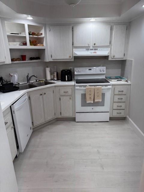 A kitchen features white cabinets, light wood-look flooring, and white appliances — 111 N Pompano Beach Boulevard # 1005, Pompano Beach FL 33062, POMPANO BEACH, FL