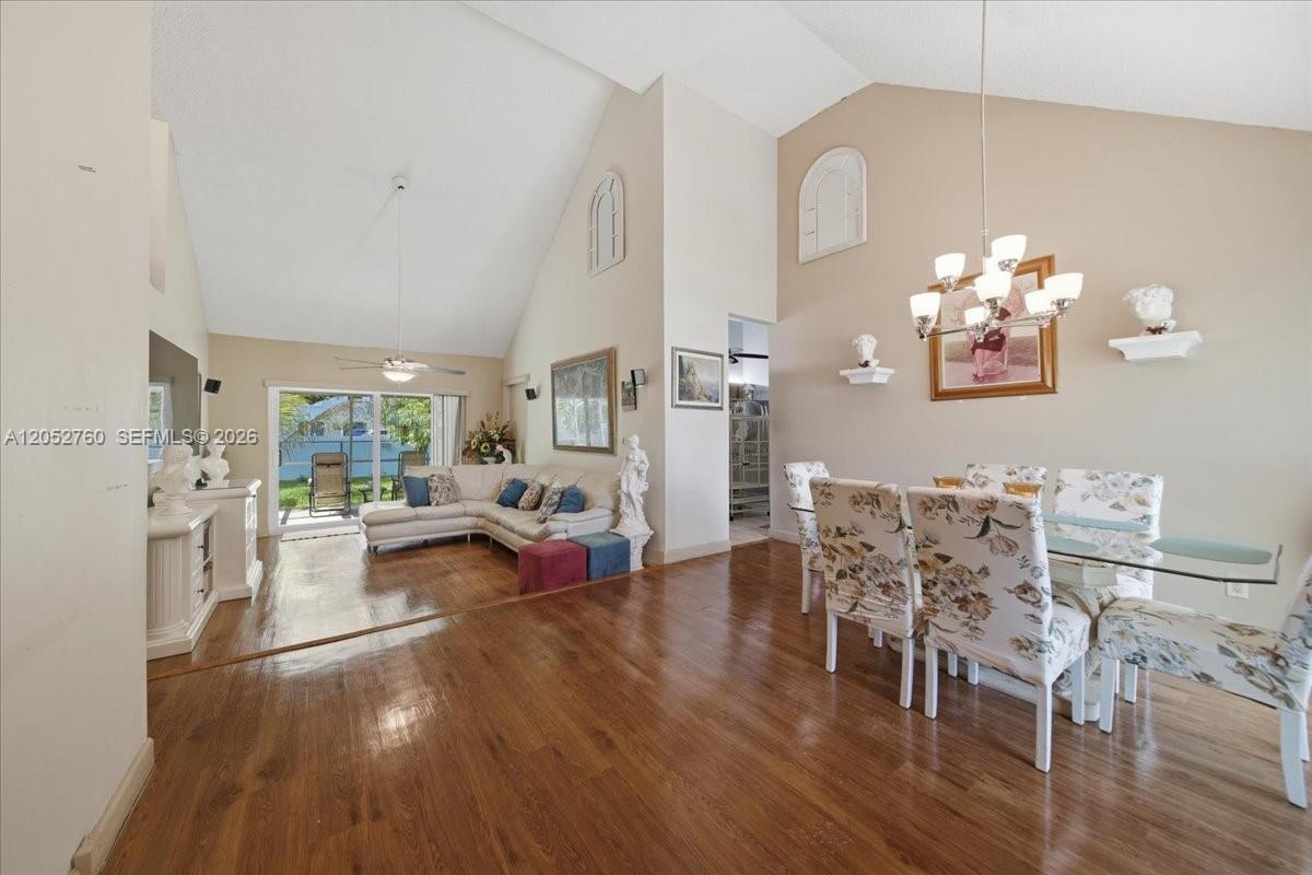 A living and dining area features vaulted ceilings, hardwood floors, and a glass-topped table — 9050 Crescent Dr, Miramar FL 33025, MIRAMAR, FL
