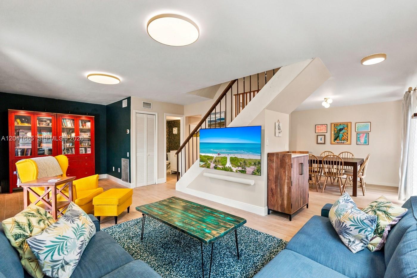 A living room features a blue sofa, yellow armchairs, a television, and a dining area — 6231 SW 116th Pl # G, Miami FL 33173, MIAMI, FL