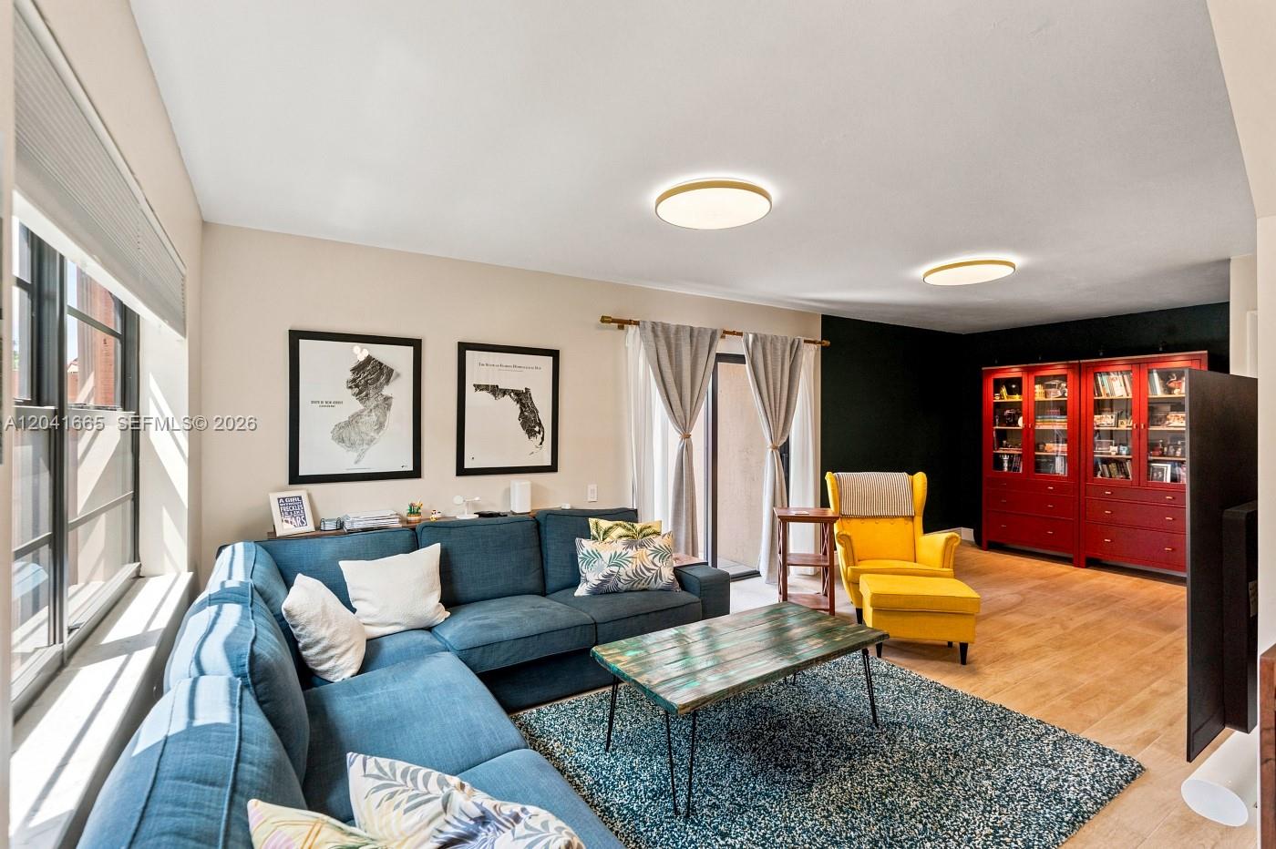 A living room features a blue sectional sofa, a yellow armchair, and red bookshelves — 6231 SW 116th Pl # G, Miami FL 33173, MIAMI, FL