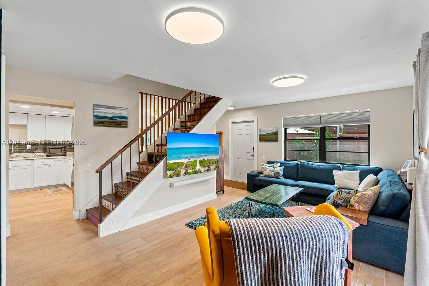 A living room features a blue sectional sofa, a yellow armchair, and a staircase — 6231 SW 116th Pl # G, Miami FL 33173, MIAMI, FL