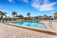 A swimming pool with a paved deck and palm trees under a blue sky — 6372 PALMA DEL MAR BOULEVARD S UNIT 219, ST PETERSBURG, FL