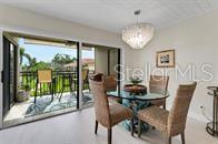 A dining area with a glass table, four chairs, a chandelier, and sliding doors to a balcony — 6372 PALMA DEL MAR BOULEVARD S UNIT 219, ST PETERSBURG, FL