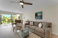 A living room features a beige sofa, glass coffee table, and sliding doors to a balcony — 6372 PALMA DEL MAR BOULEVARD S UNIT 219, ST PETERSBURG, FL