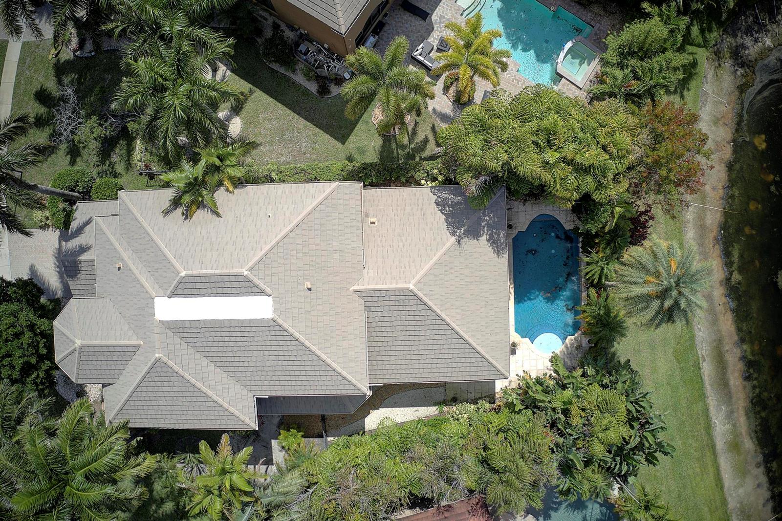 An aerial view shows a house with a tiled roof, a pool, and surrounding landscaping — 3483 Collonade Drive, Wellington FL 33449, WELLINGTON, FL