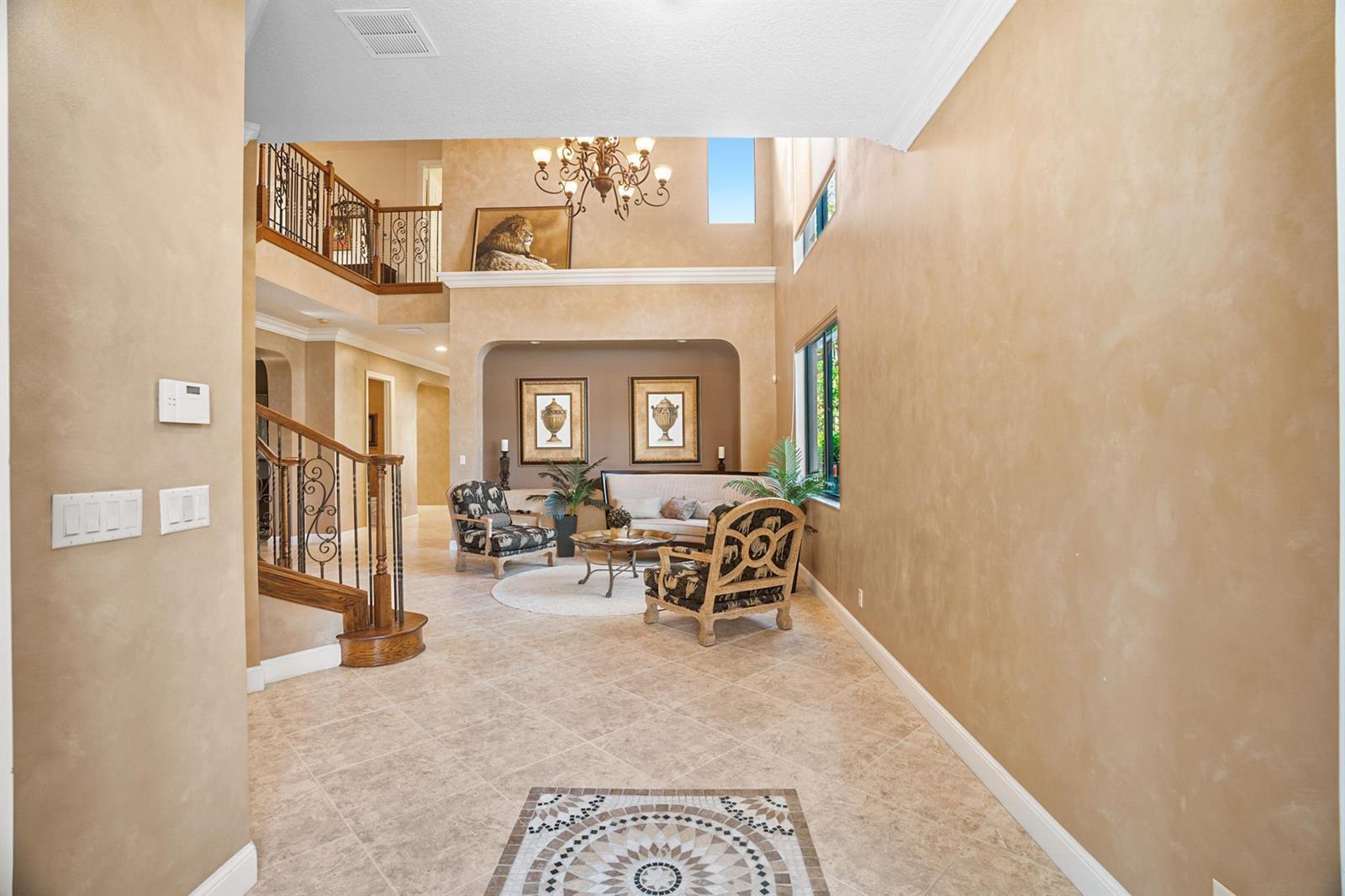 A two-story foyer features tile flooring, a wrought iron staircase, and a seating area — 3483 Collonade Drive, Wellington FL 33449, WELLINGTON, FL