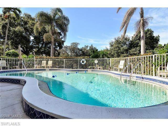 A curved swimming pool with a white fence is surrounded by palm trees and landscaping — OTHER CITY - IN THE STATE OF FLORIDA, FL