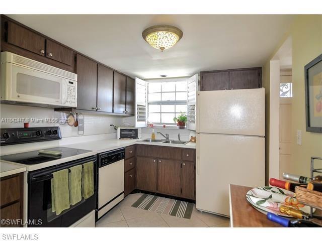 A kitchen features dark wood cabinets, a white refrigerator, and a black stove — OTHER CITY - IN THE STATE OF FLORIDA, FL