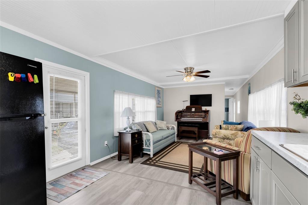 A living room features light blue walls, wood-look flooring, a sofa, and an upright piano — 6835 ANAPA COURT, NORTH PORT, FL