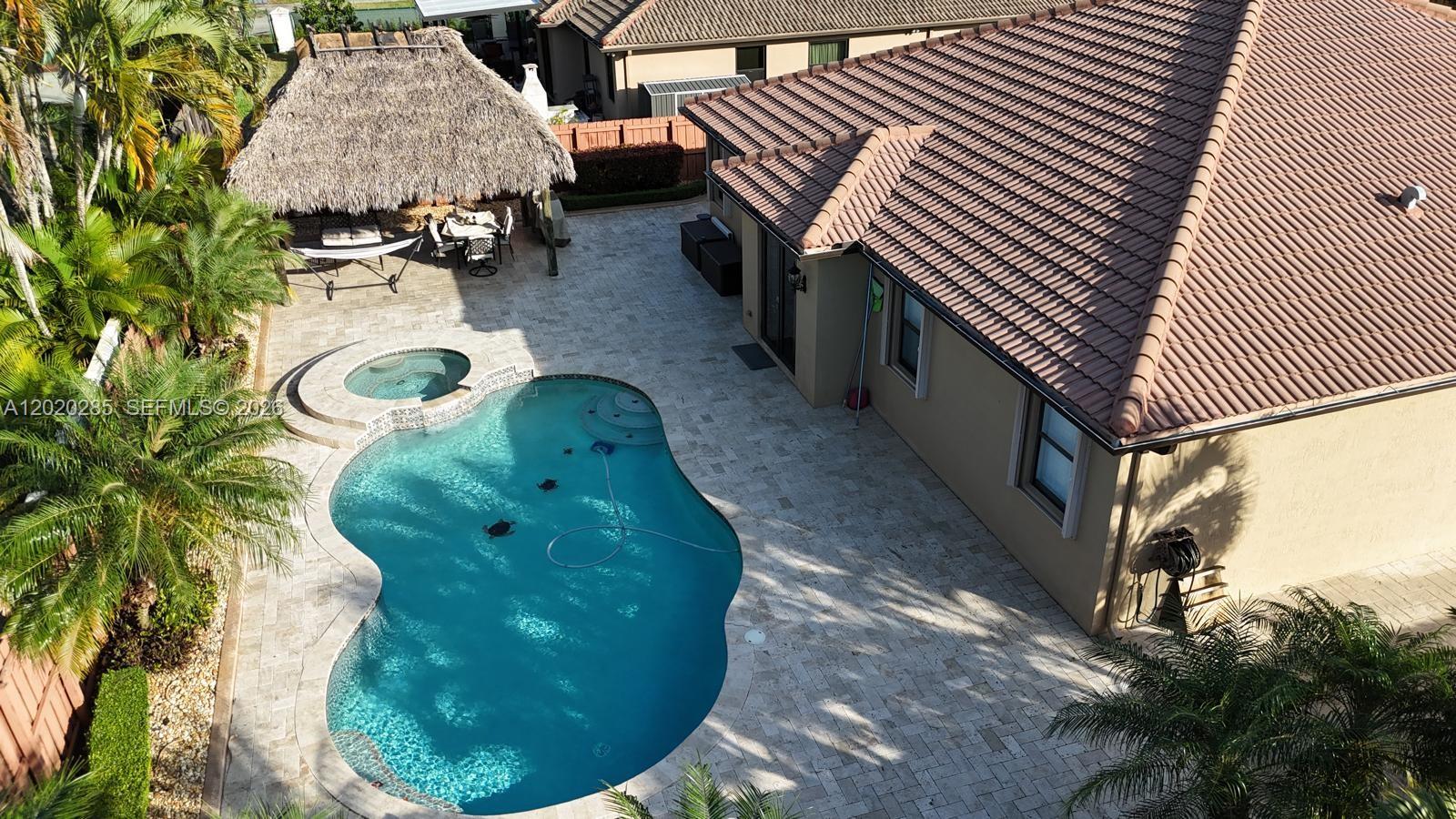 An aerial view shows a backyard with a swimming pool, spa, and a thatched-roof gazebo — 15413 SW 116th Ter, Miami FL 33196, MIAMI, FL