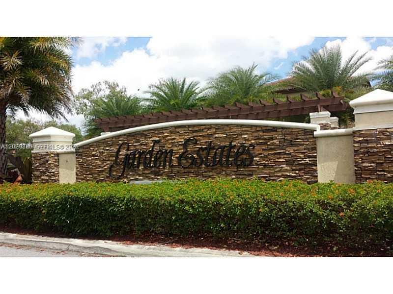 A stone wall with the words Garden Estates sits behind a hedge and palm trees — 15413 SW 116th Ter, Miami FL 33196, MIAMI, FL