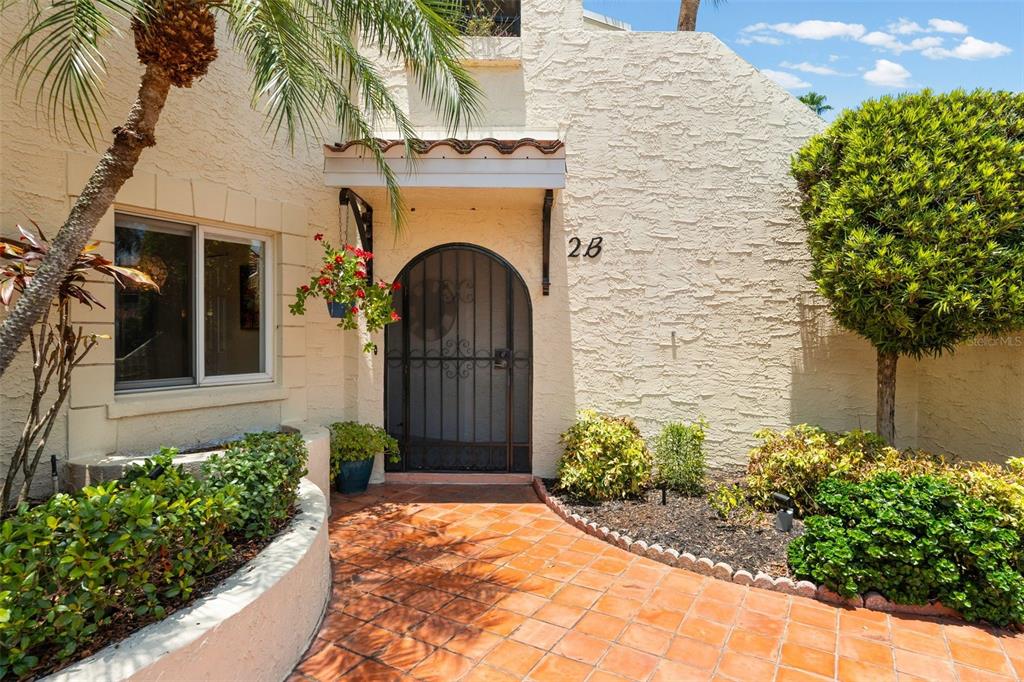 An arched front door with a metal security gate sits at the end of a walkway — 6101 34TH STREET W UNIT 2B, BRADENTON, FL