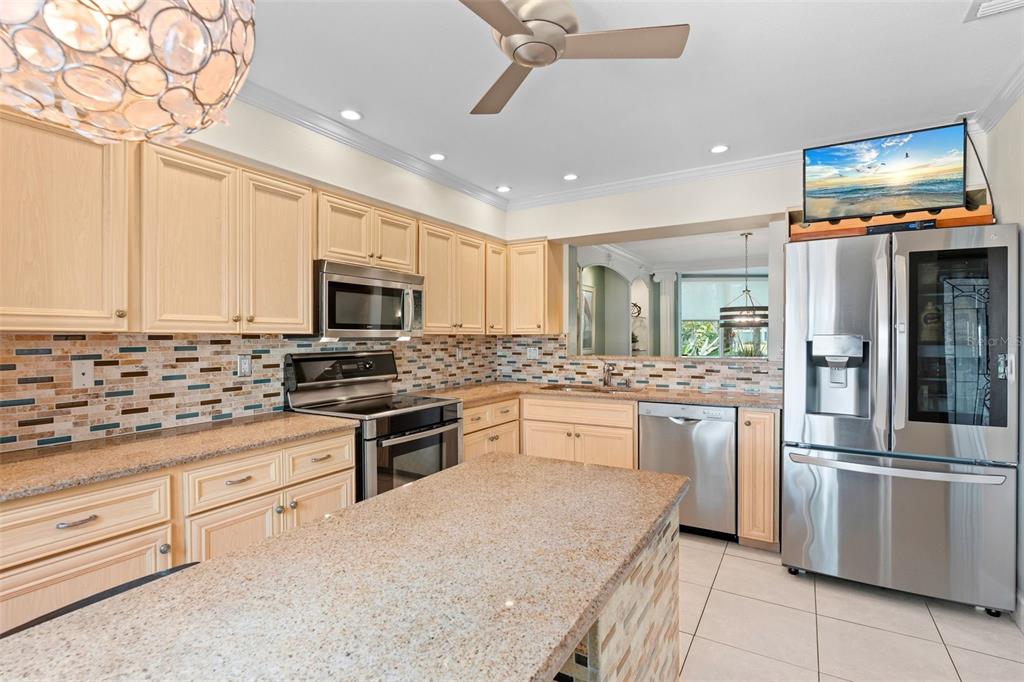 A kitchen featuring light wood cabinets, granite countertops, stainless steel appliances, and a tiled backsplash — 6101 34TH STREET W UNIT 2B, BRADENTON, FL