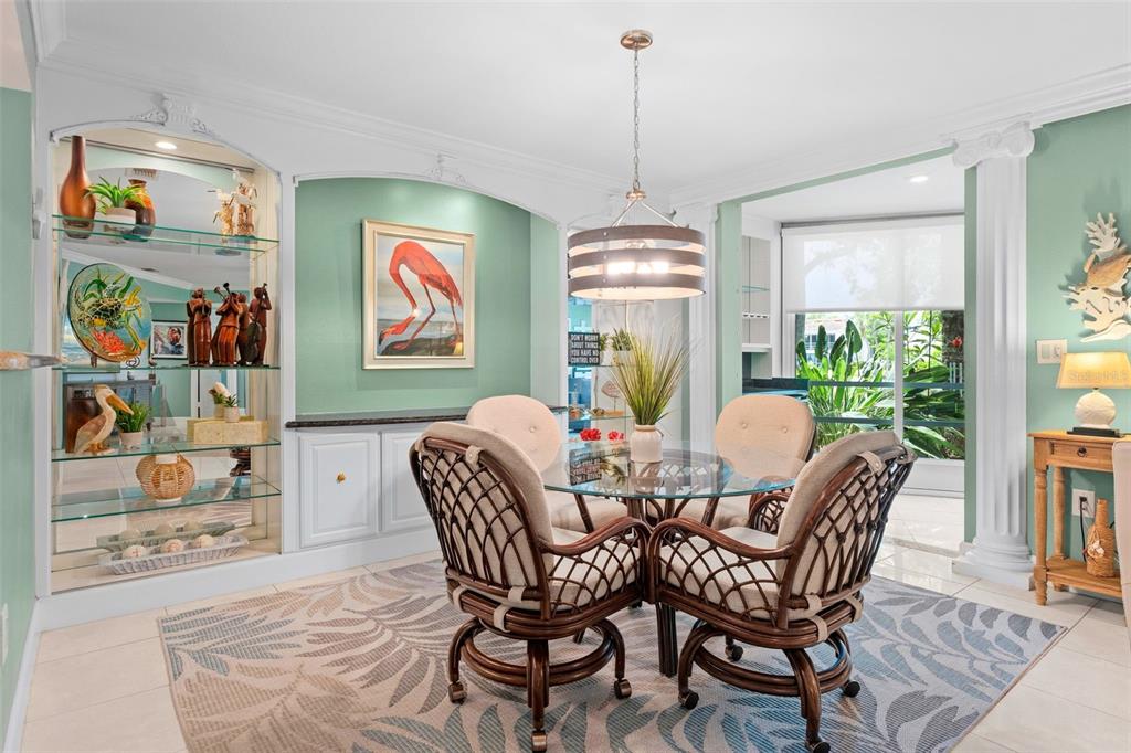 A dining room features a glass-topped table, wicker chairs, a patterned rug, and built-in shelving — 6101 34TH STREET W UNIT 2B, BRADENTON, FL