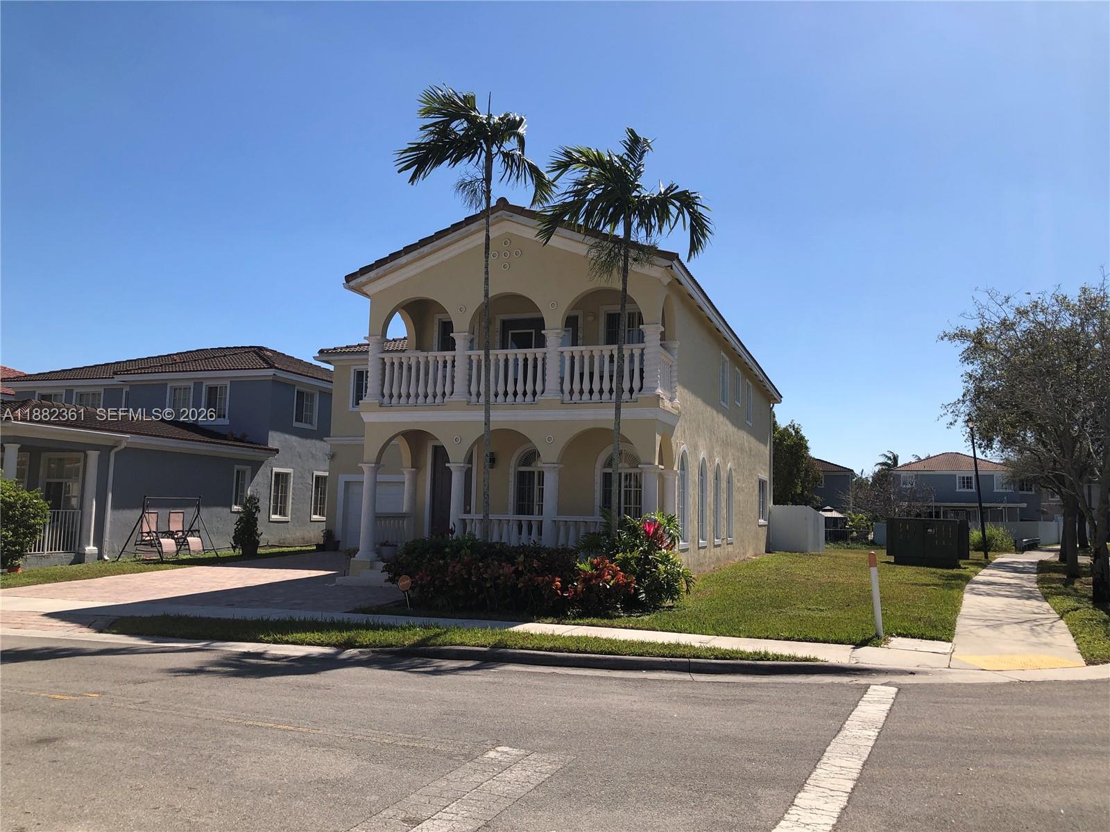 A two-story yellow house with a double-level arched balcony and two palm trees in front — 13986 SW 276th Way, Homestead FL 33032, HOMESTEAD, FL