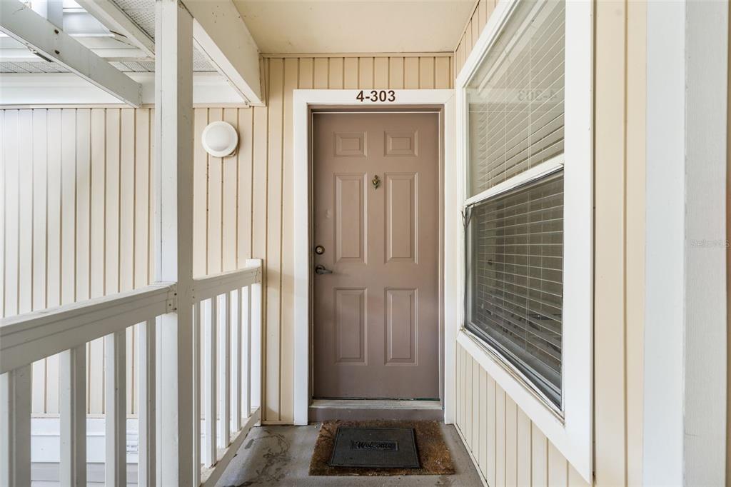 A beige apartment door with the number 4-303 is situated on an outdoor walkway — 4000 SW 23RD STREET UNIT 4-303, GAINESVILLE, FL