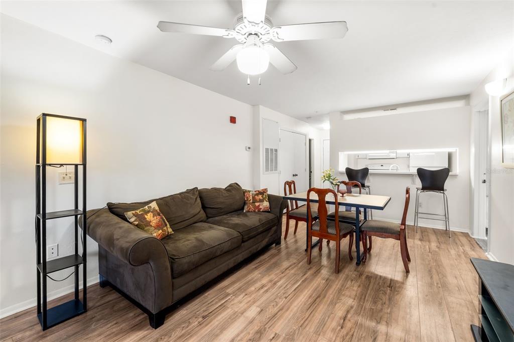 A living and dining area features a brown sofa, a dining table, and wood-look flooring — 4000 SW 23RD STREET UNIT 4-303, GAINESVILLE, FL