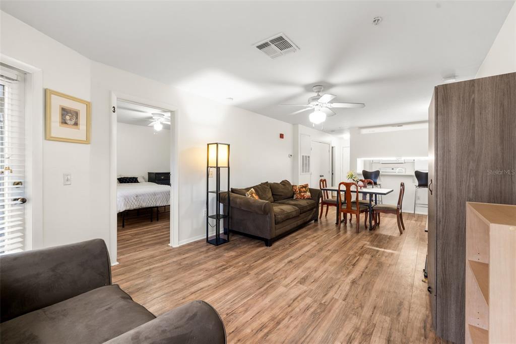 A living room with wood-look flooring, a brown sofa, and an adjacent dining area — 4000 SW 23RD STREET UNIT 4-303, GAINESVILLE, FL