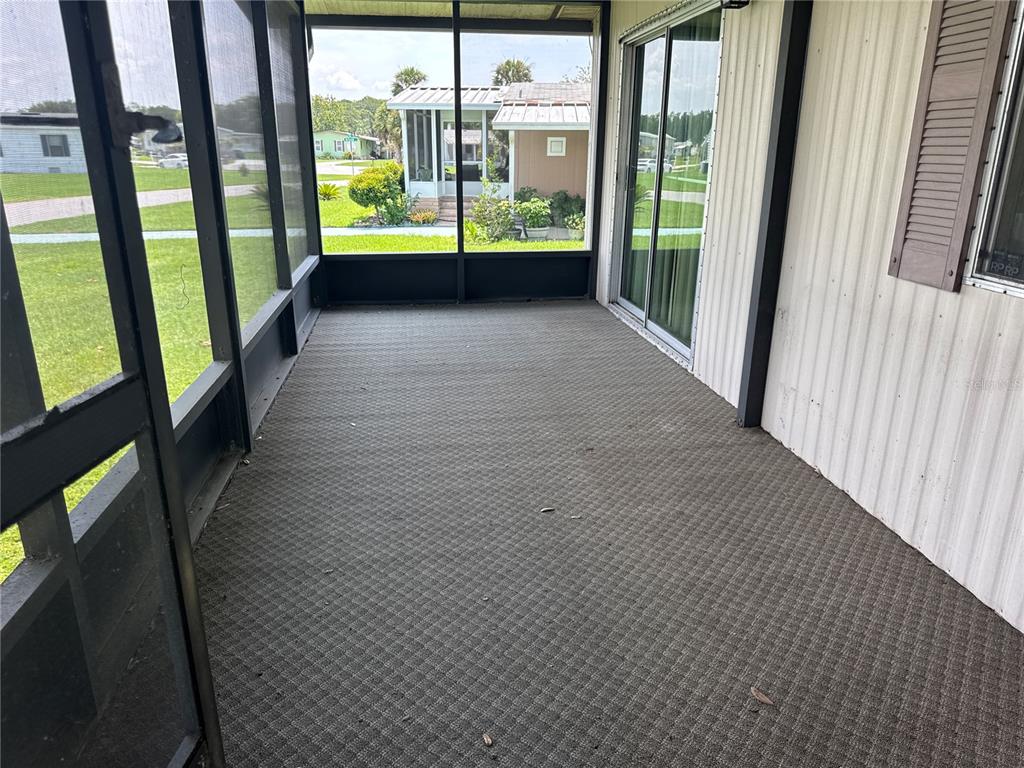 A screened-in porch with gray carpet flooring and sliding glass doors leading indoors — 2642 MCDANIEL DRIVE, KISSIMMEE, FL