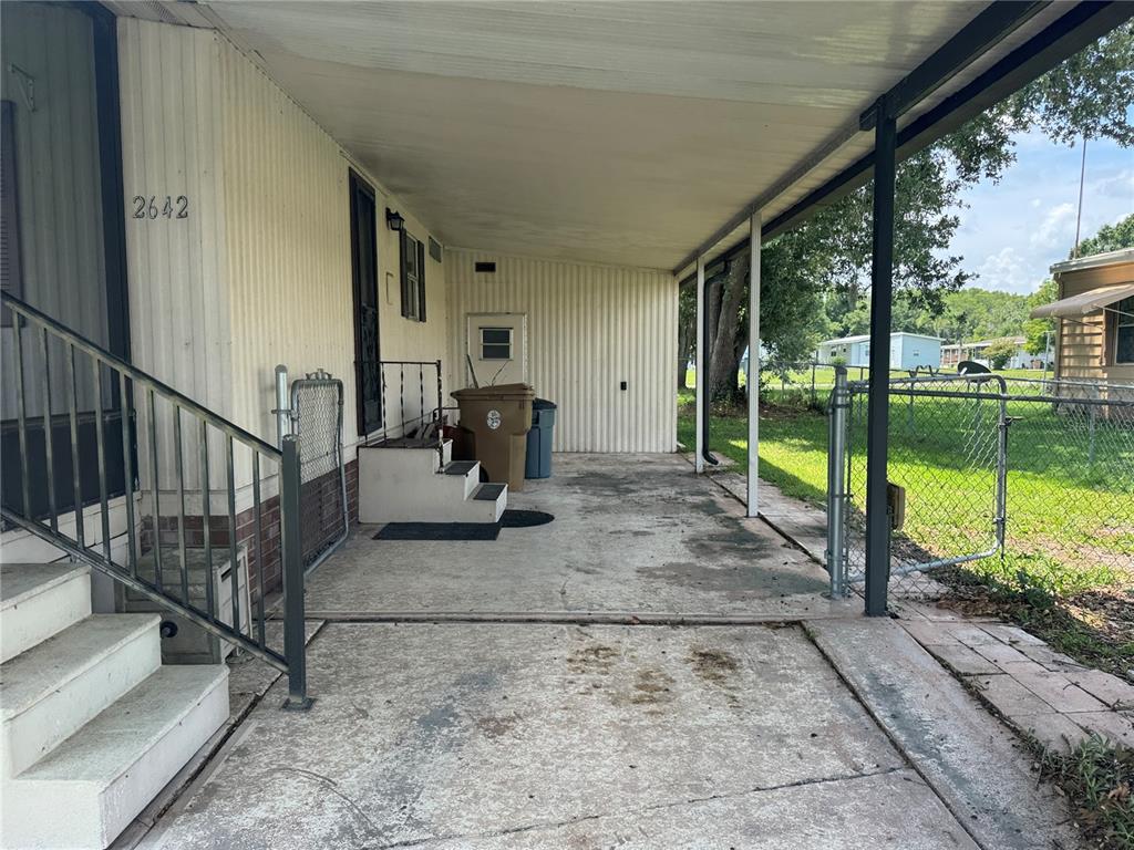 A concrete carport with a metal roof and stairs leading to a mobile home entrance — 2642 MCDANIEL DRIVE, KISSIMMEE, FL