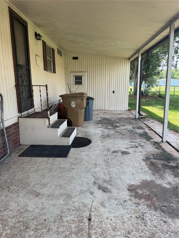 A covered concrete patio features a set of steps leading to a side entrance door — 2642 MCDANIEL DRIVE, KISSIMMEE, FL