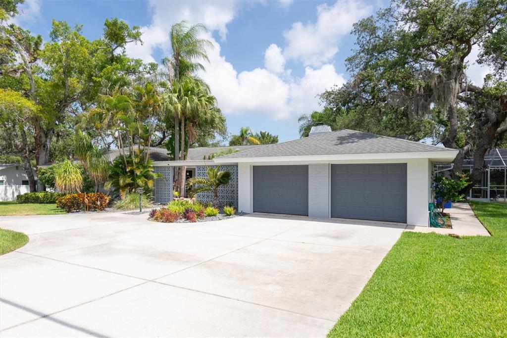 A single-story house with a two-car garage, a concrete driveway, and lush tropical landscaping — 1350 FAIRWAY DRIVE, DUNEDIN, FL
