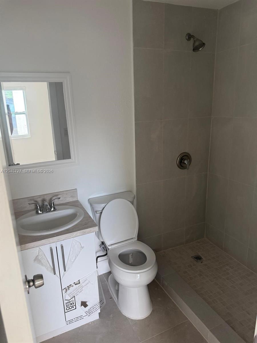 A bathroom features a white vanity, a toilet, and a tiled walk-in shower — 2328 NW 80th St, Miami FL 33147, MIAMI, FL