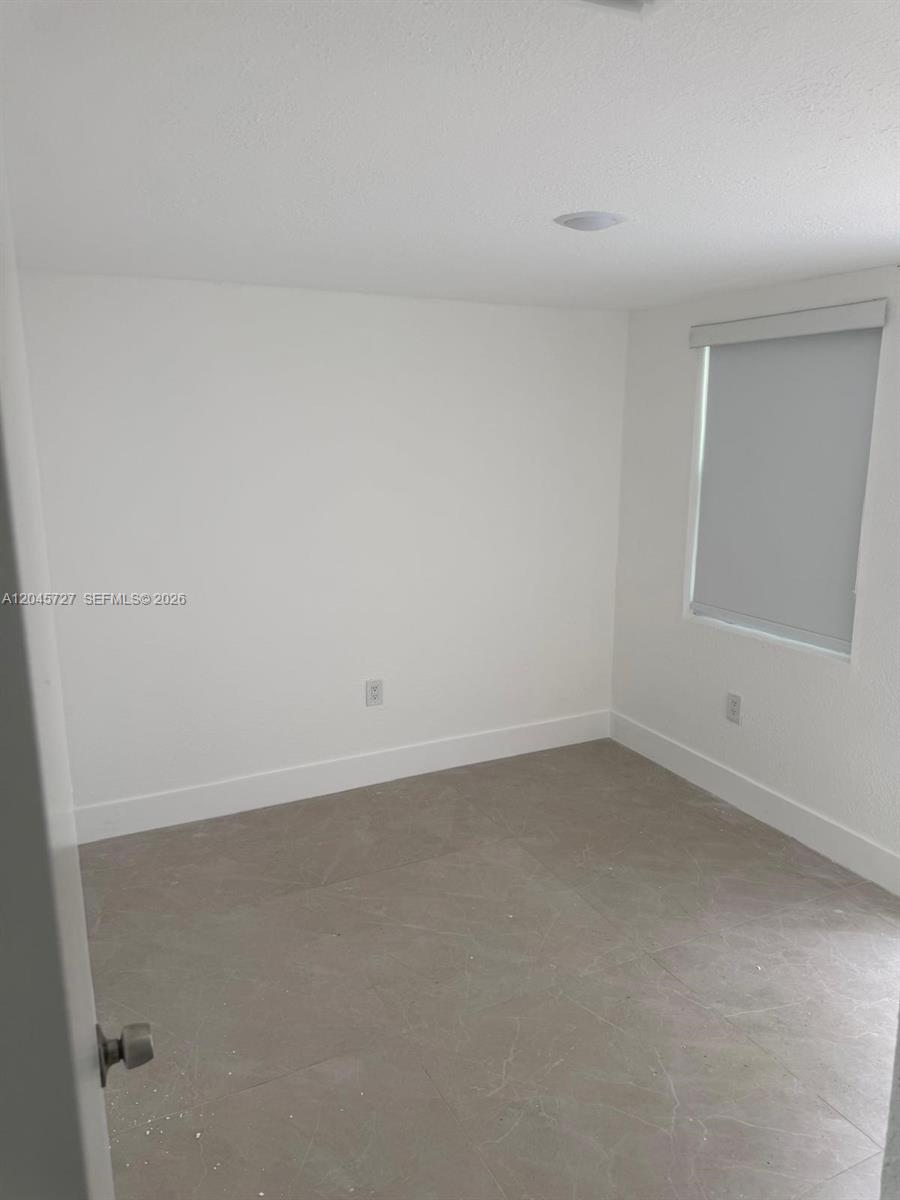 A small, empty room features white walls, light-colored tile flooring, and a single window — 2328 NW 80th St, Miami FL 33147, MIAMI, FL