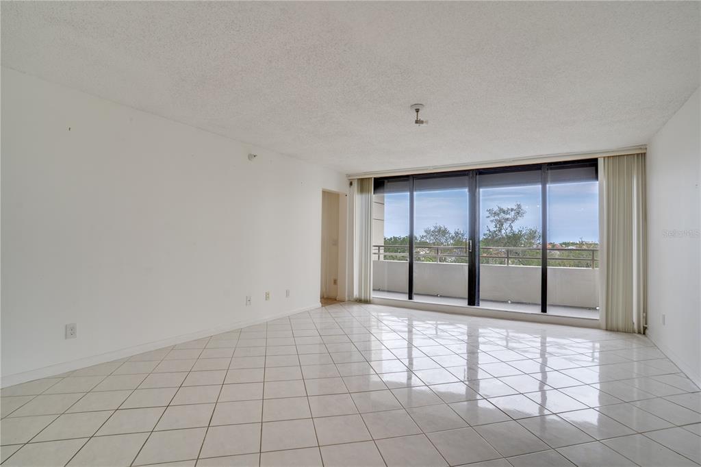 An empty room with white walls, white tile flooring, and a large sliding glass door — 5940 PELICAN BAY PLAZA S UNIT 504, ST PETERSBURG, FL