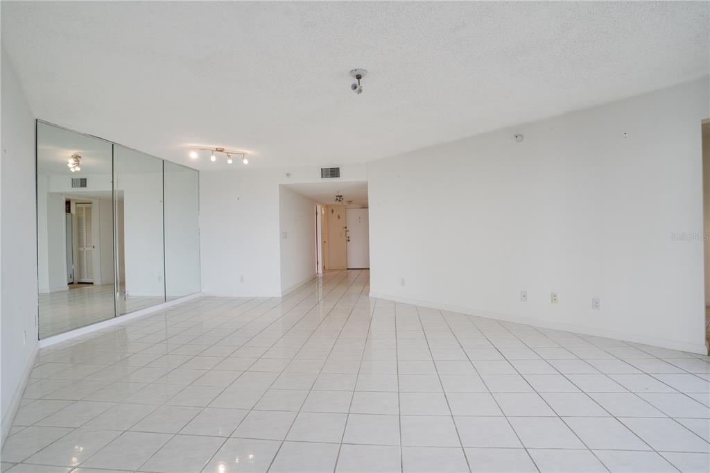 An empty room with white tiled floors, white walls, and a large mirrored wall — 5940 PELICAN BAY PLAZA S UNIT 504, ST PETERSBURG, FL