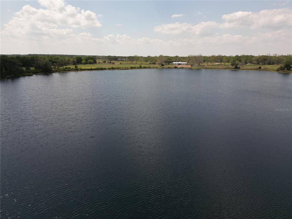 An aerial view of a large lake with a house visible on the distant shore — 3430 LAKE DIANE ROAD, TAVARES, FL