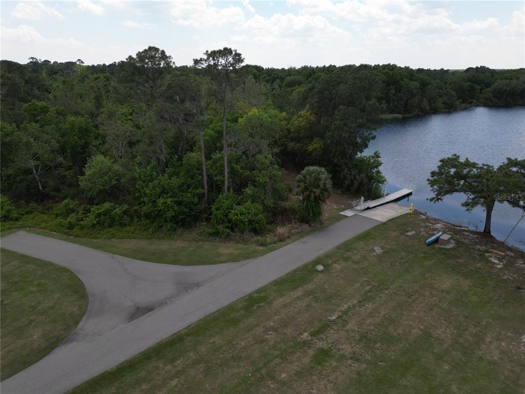 An aerial view shows a paved boat ramp leading into a lake near wooded land — 3430 LAKE DIANE ROAD, TAVARES, FL