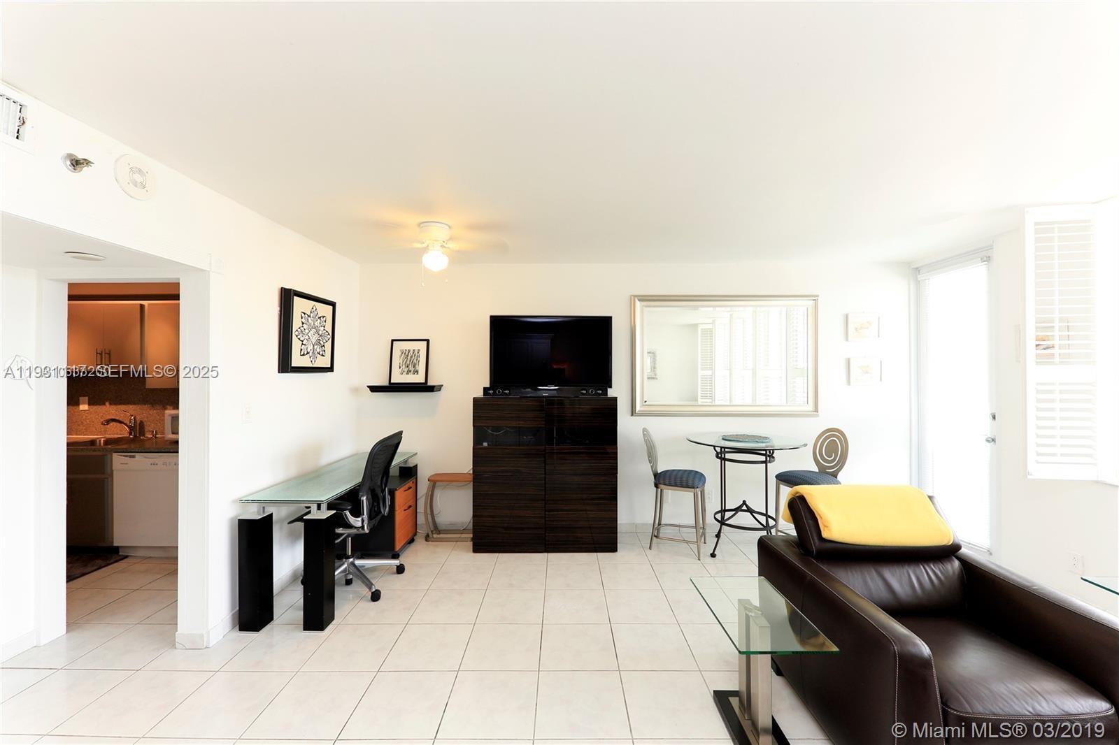 A living room features a desk, a television on a cabinet, and a dining table — 100 Lincoln Rd # 509, Miami Beach FL 33139, MIAMI BEACH, FL
